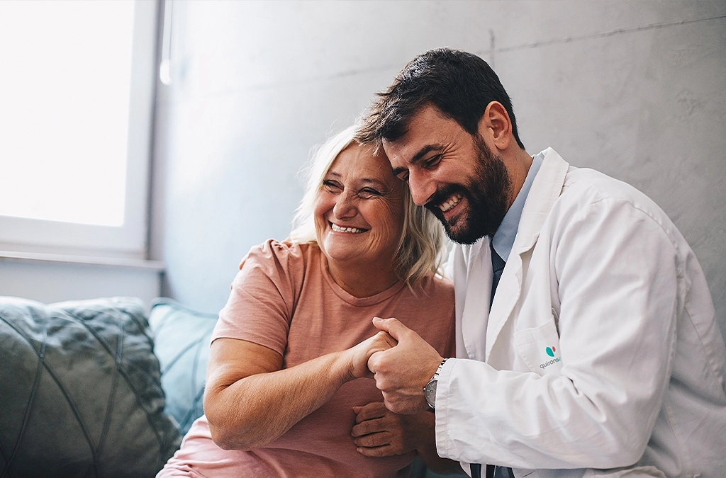 Ein Arzt umarmt eine Patientin und hält ihre Hand, beide lächeln (Foto)